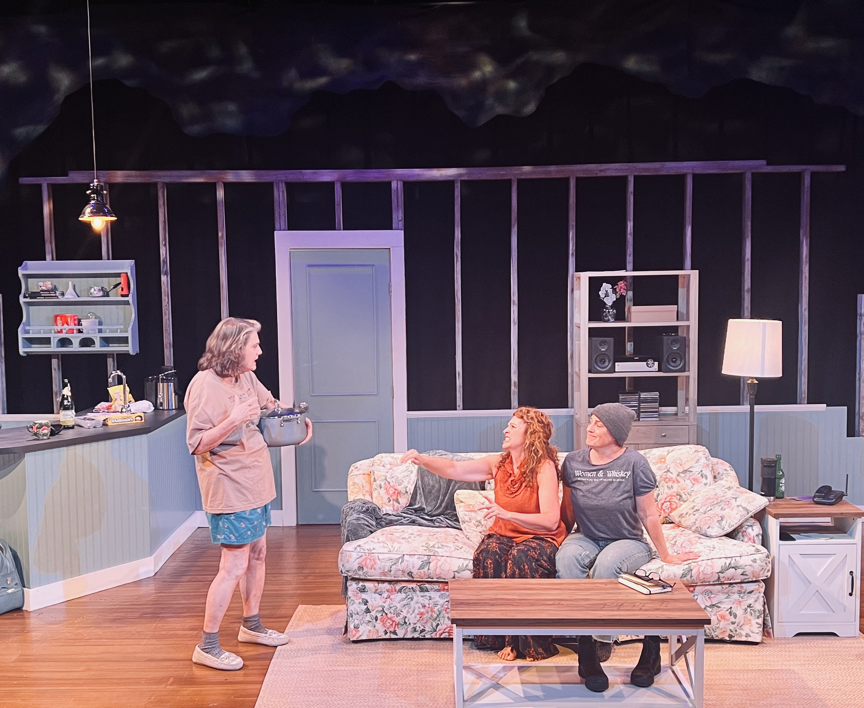 Three performers sharing a charged moment in the beach cottage in The Fade-Away Advantage
