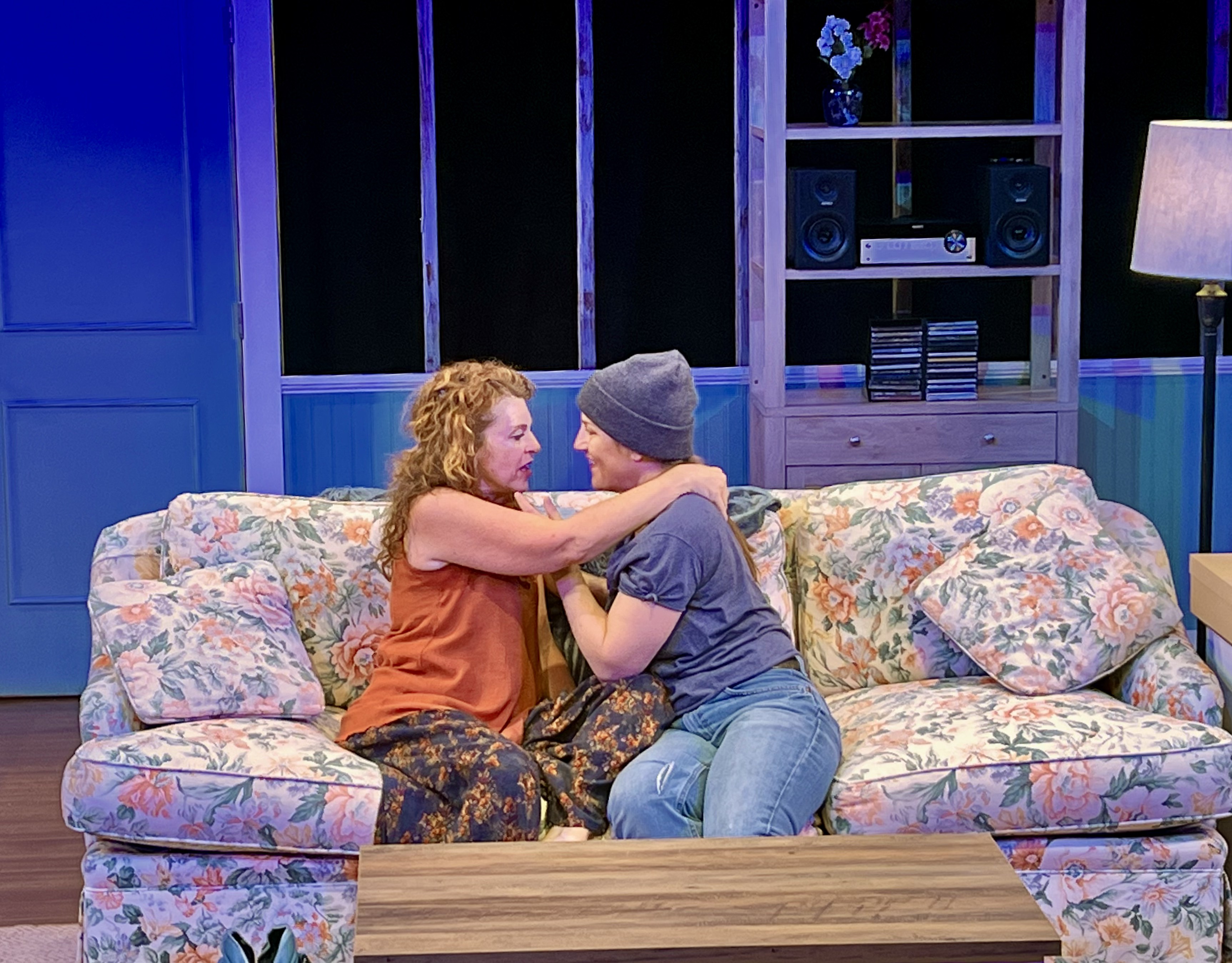 Two lifelong friends embracing on the cottage sofa in The Fade-Away Advantage